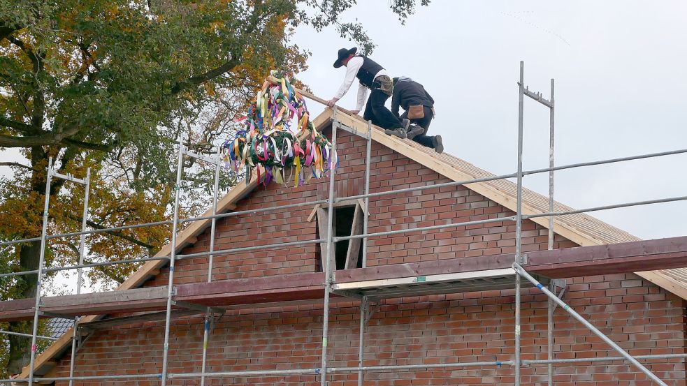 Dachdecker brachten den Richtkranz am Giebel an. Foto: Kruse