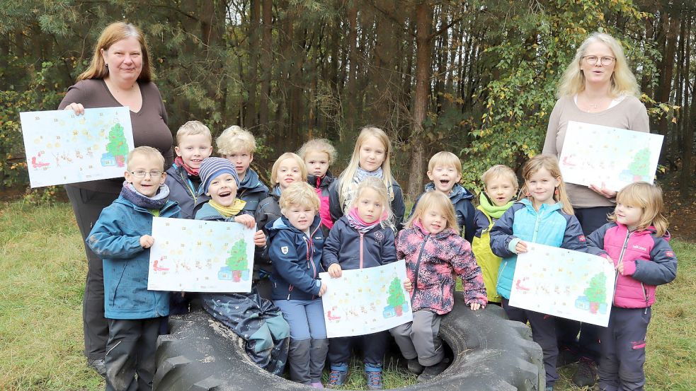 Einen eigenen Adventskalender hat der Förderverein der Kita und Grundschule Sonnentau Elisabethfehn entworfen. Stolz zeigen die Kinder des Waldkindergartens „De Landkieker“ einige Exemplare. Das Deckblatt haben sie selbst gezeichnet. Foto: Passmann