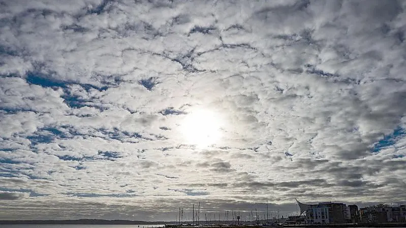 Wolken verdecken die Sonne, die auf den Hafen von Eckernförde (Schleswig-Holstein) scheint. Foto: Frank Molter/dpa