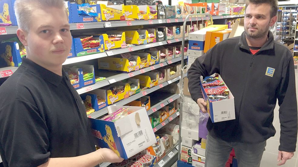 Dennis Schoon (rechts), Marktleiter von Edeka in Remels, und Auszubildender Joost Thiele, räumen hier Süßigkeiten in ein Regal. Foto: Schneider-Berents