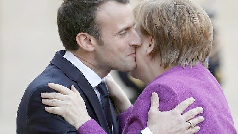 Frankreichs Präsident Emmanuel Macron und Noch-Bundeskanzlerin Angela Merkel geben sich Küsschen. Foto: Francois Mori/AP/dpa