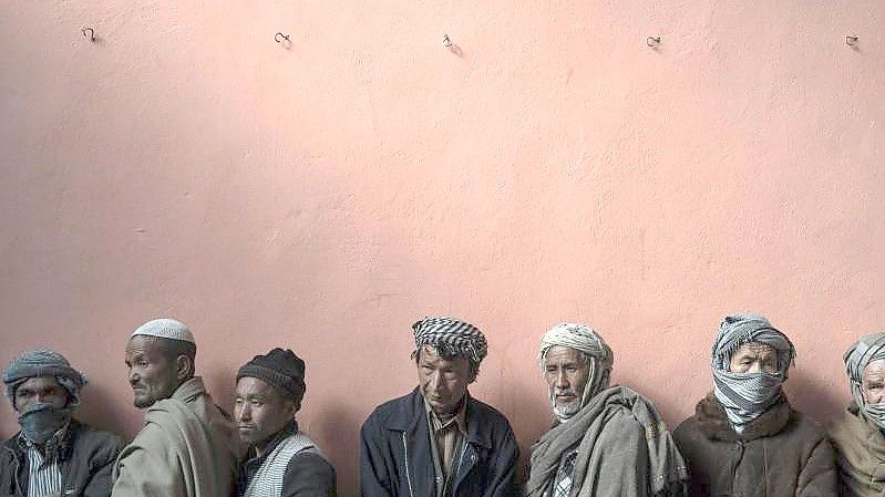 Männer warten in einer Schlange, um bei einer vom Welternährungsprogramm (WFP) organisierten Geldverteilung Bargeld zu erhalten. Foto: Bram Janssen/AP/dpa