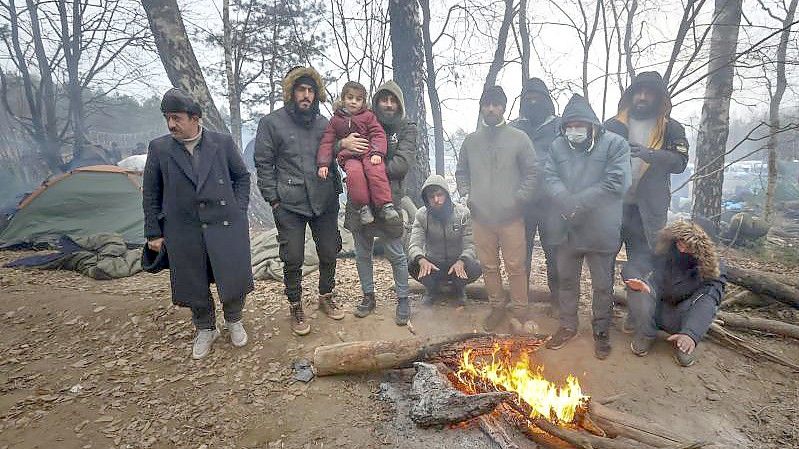 Migranten versammeln sich an der belarussisch-polnischen Grenze an einem Feuer, um sich zu wärmen. Foto: Ramil Nasibulin/BelTA/AP/dpa