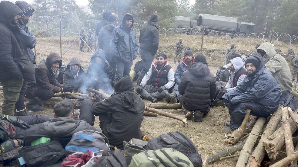 Migranten versammeln sich an der belarussisch-polnischen Grenze an einem Feuer, um sich zu wärmen. In der Grenzregion ist keine Entspannung der Lage in Sicht. Foto: Shcheglov/BelTA/AP/dpa