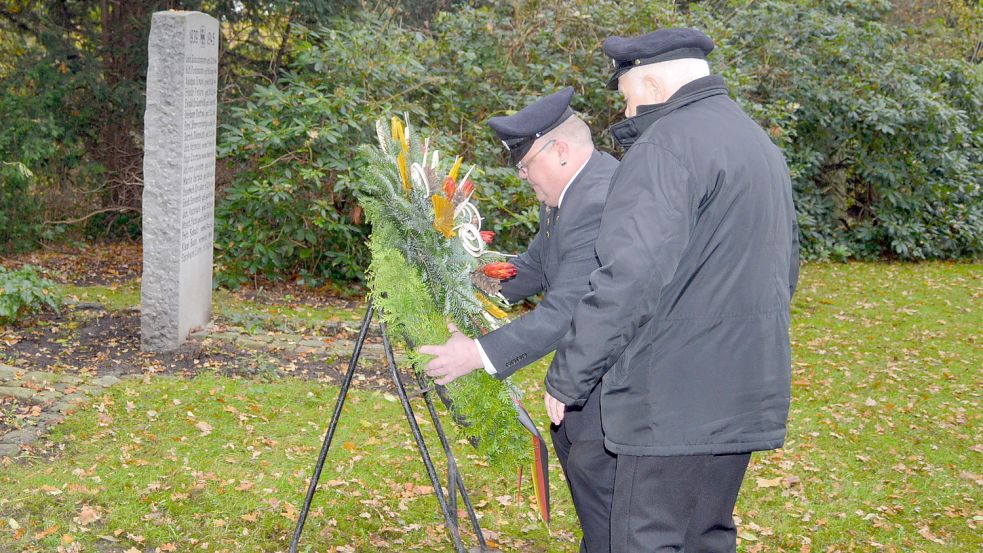 Zwei Mitglieder der Kyffhäuserkameradschaft Backemoor legen am Ehrenmal bei der Kirche einen Kranz nieder. Foto: Weers