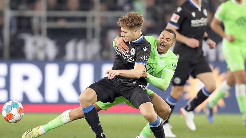 Bielefelds Cedric Brunner (l) und Wolfsburgs Lukas Nmecha kämpfen um den Ball. Foto: Friso Gentsch/dpa