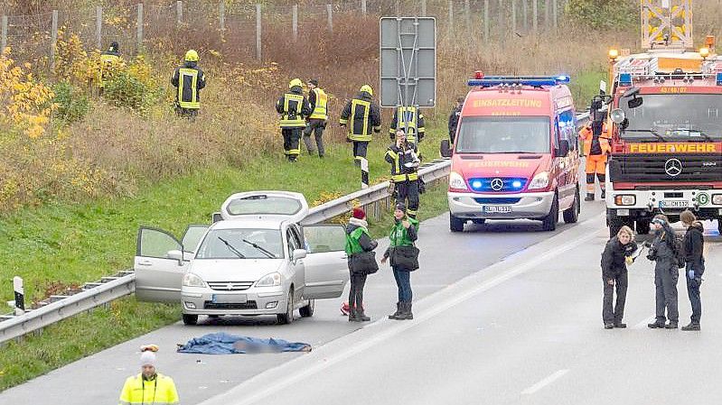 Polizisten und Rettungskräfte stehen neben dem Leichnam der jungen Frau auf der Autobahn 7. Foto: Benjamin Nolte/dpa
