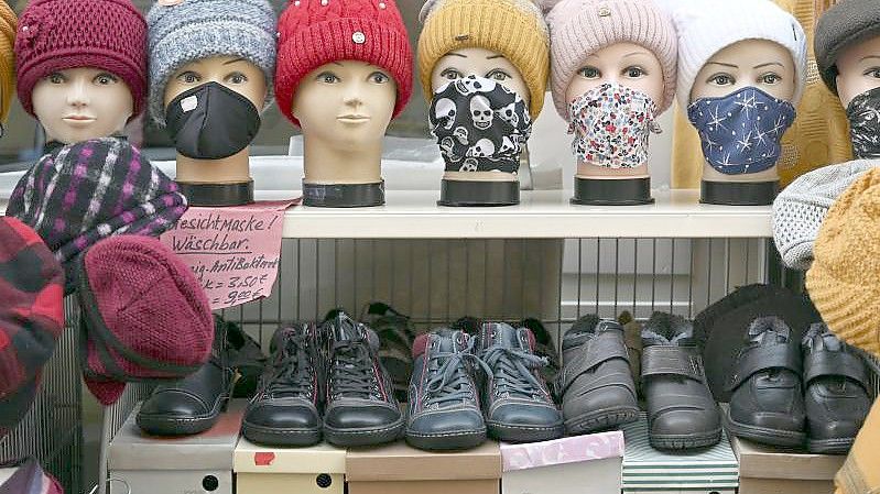 Schaufensterpuppenköpfe mit Gesichtsmasken, Tüchern und Mützen stehen vor einem Bekleidungsgeschäft in der Altstadt von Mühlhausen. Foto: Martin Schutt/dpa-Zentralbild/dpa