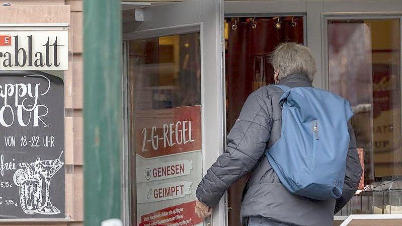 Ein Mann betritt ein Café in der Mainzer Altstadt, an dessen Tür auf die 2-G-Regel hingewiesen wird. Foto: Helmut Fricke/dpa