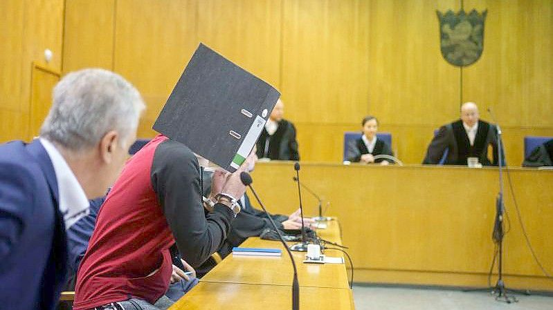 Mit einem Aktenordner vor dem Gesicht nimmt der Iraker Taha Al-J. vor der Urteilsverkündung im Frankfurter Oberlandesgericht auf der Anklagebank Platz. Foto: Frank Rumpenhorst/dpa-Pool/dpa