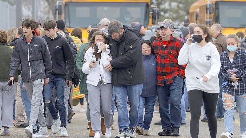 Eltern verlassen mit ihren Kindern einen Parkplatz, wo sich viele Schüler nach einer Schießerei an der Oxford High School im US-Bundesstaat Michigan versammelt haben. Foto: Eric Seals/Detroit Free Press via AP/dpa