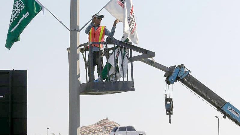 Ein Mitarbeiter hängt Flaggen an der Rennstrecke des Corniche Circuit auf: Die Formel 1 gastiert erstmals in Saudi-Arabien. Foto: Amr Nabil/AP/dpa