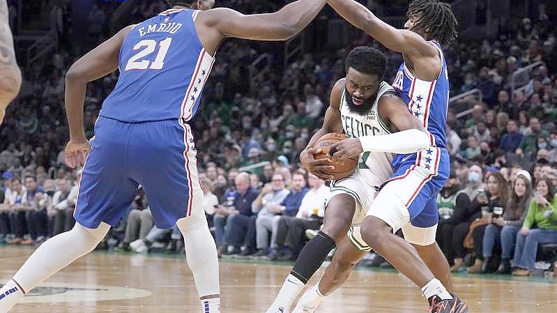 Boston Celtics-Guard Jaylen Brown (M) gegen Philadelphia 76ers-Guard Tyrese Maxey (r) und Center Joel Embiid. Foto: Charles Krupa/AP/dpa