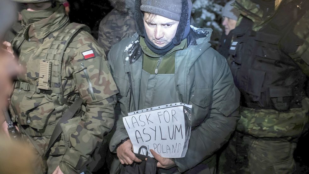 Bitte um Asyl: Ein Syrer, der von polnischen Grenzschützern in Gewahrsam genommen wurde, hält ein Papier mit der Aufschrift „I ask for asylum in Poland“ in den Händen. In den vergangenen Monaten ist eine große Zahl von Migranten aus dem Nahen Osten über Belarus an die polnische Ostgrenze gelangt, die auch die Ostgrenze der EU ist. Foto: Michal Kosc/AP
