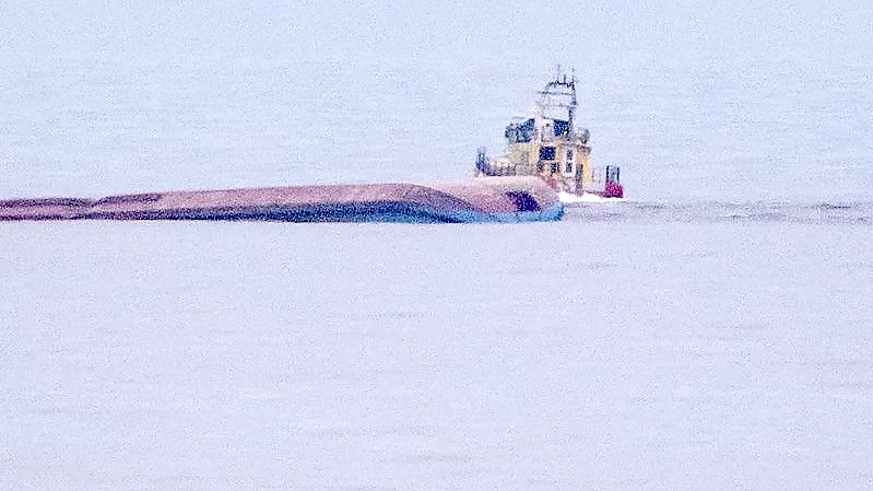 Ein Rettungsboot fährt an dem mit Kiel nach oben liegenden dänischen Frachtschiff Karin Hoej vorbei. Foto: Johan Nilsson/TT NEWS AGENCY/AP/dpa