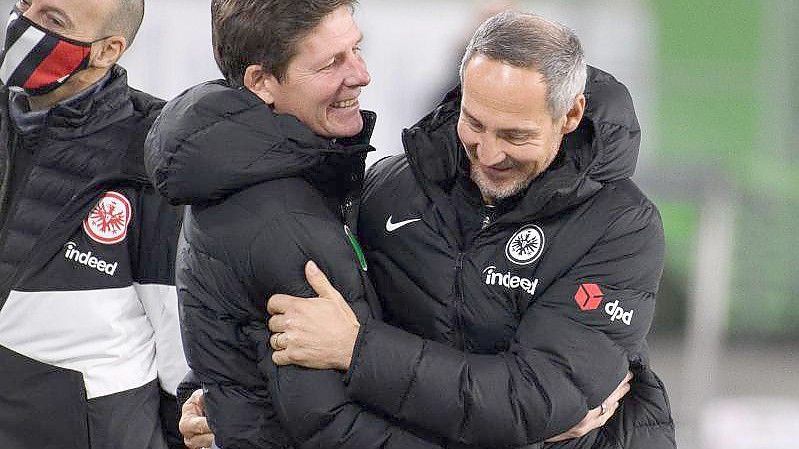 Wolfsburgs Trainer Oliver Glasner (M) und Frankfurts Trainer Adi Hütter (r) begrüßen sich vor einem Spiel. Foto: Swen Pförtner/dpa/Archivbild