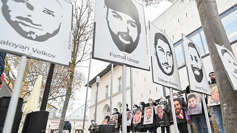Angehörige der Opfer des rassistischen Anschlags von Hanau 2020 halten bei einer Mahnwache Fotos der Opfer. Foto: Arne Dedert/dpa