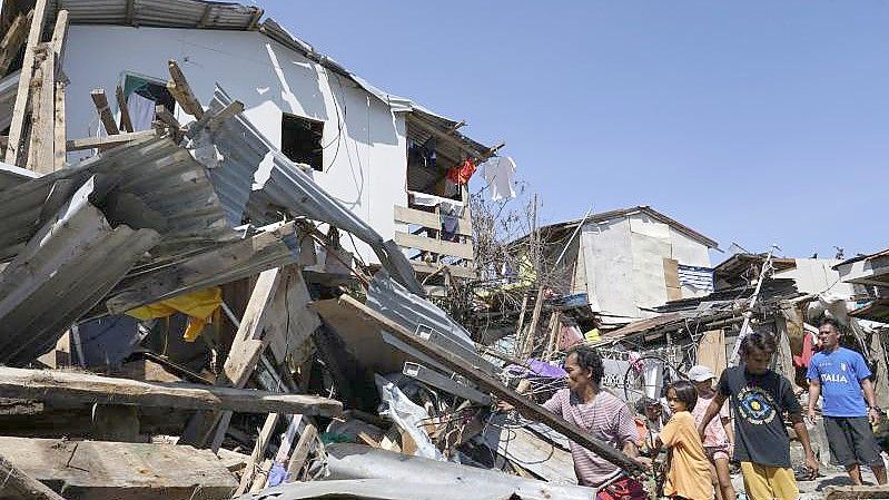 Bewohner suchen in den zerstörten Häusern nach Habseligkeiten. Foto: Jay Labra/AP/dpa