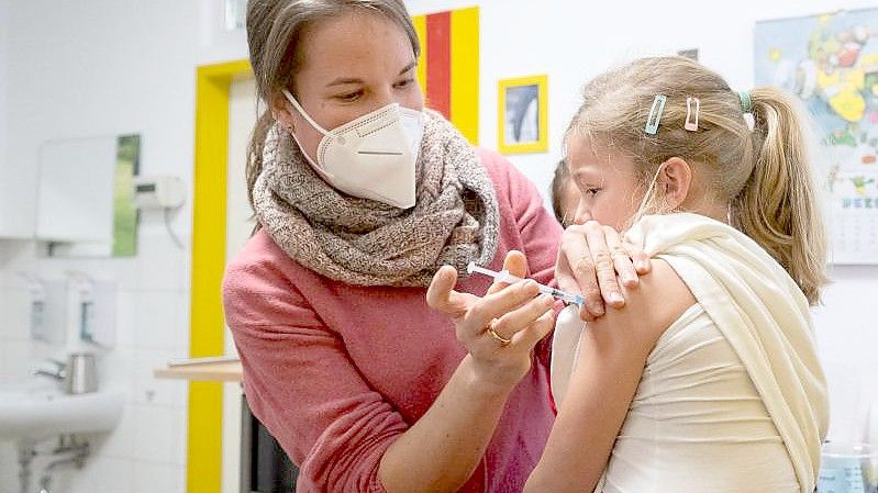 Die Kinderärztin Carmen Dompert impft in ihrer Praxis ihre Tochter Johanna gegen das Coronavirus. Foto: Bernd Weißbrod/dpa