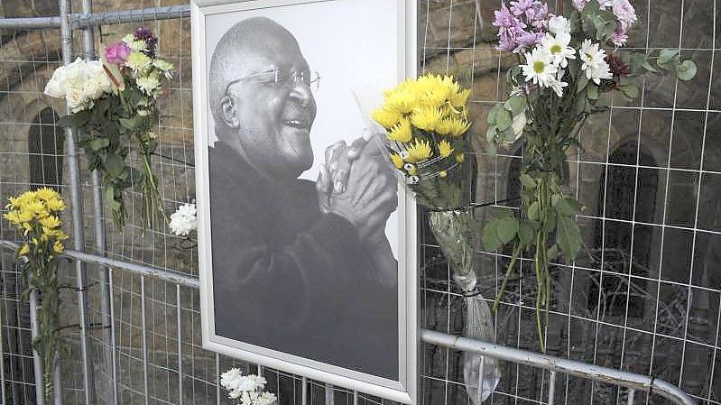 Blumen und ein Foto von Desmond Tutu an einem Gerüst in der St. George's Kathedrale in Kapstadt. Foto: AP/dpa