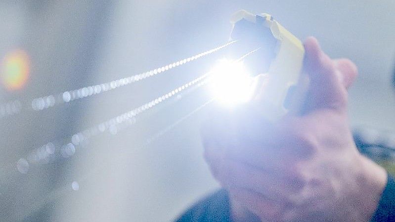 Ein Polizeibeamter demonstriert einen Schuss mit einem Taser. Foto: Rolf Vennenbernd/dpa