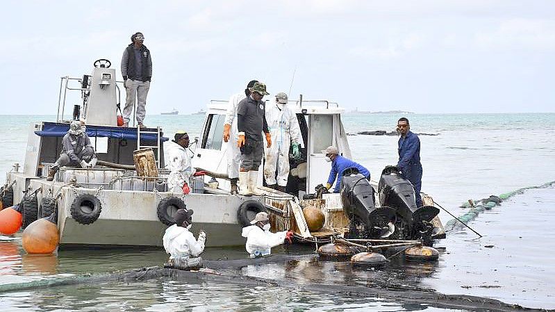 Arbeiter versuchen die Ausbreitung des Ölteppichs zu verhindern. Ein Frachter war zuvor auf Grund gelaufen. Foto: Ajai Daby/XinHua/dpa