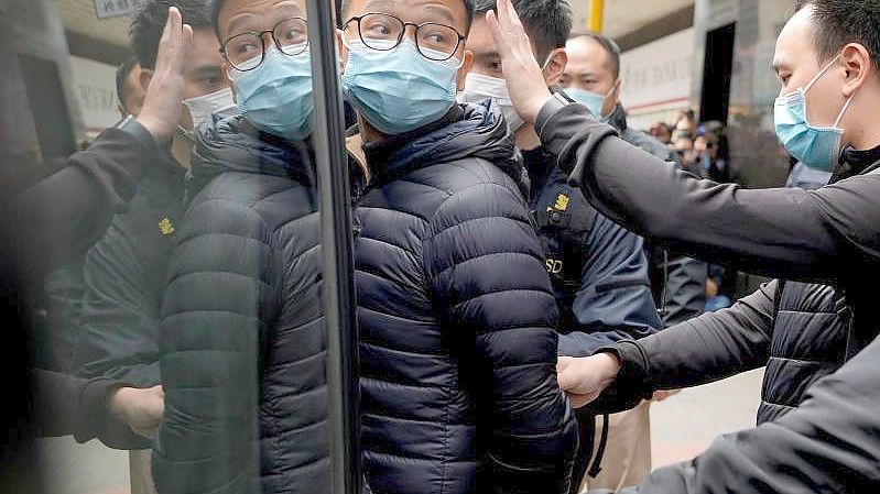 Patrick Lam (l), Herausgeber der Online-Publikation „Stand News“, wird von Polizeibeamten in einen Lieferwagen eskortiert. Foto: Vincent Yu/AP/dpa