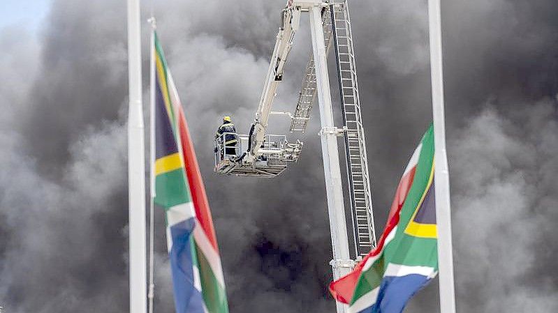 Dicke, schwarze Rauchsäulen steigen aus dem Parlamentsgebäude auf. Foto: Jerome Delay/AP/dpa