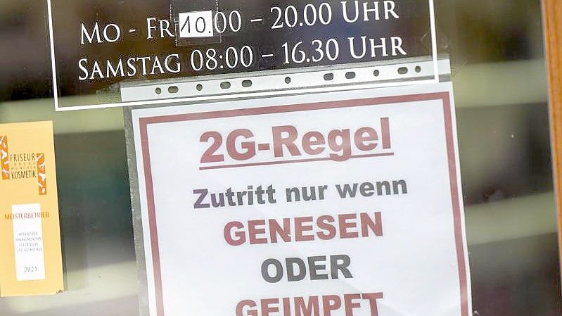 Ein Schild zur „2G-Regel“ hängt an der Eingangstür eines Münchner Friseurladens. Foto: Peter Kneffel/dpa