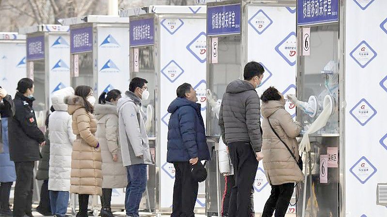 Menschen warten im Pekinger Stadtbezirk Xicheng im Rahmen eines Corona-Massentests vor Test-Kabinen. Foto: -/kyodo/dpa