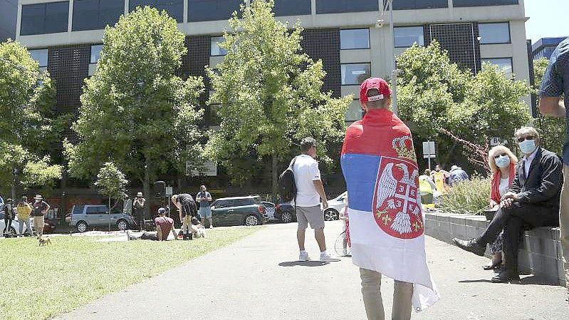 Ein Fan des serbischen Tennisspielers Novak Djokovic steht vor dem Park Hotel in Melbourne, in dem Djokovic untergebracht wird. Foto: Hamish Blair/AP/dpa
