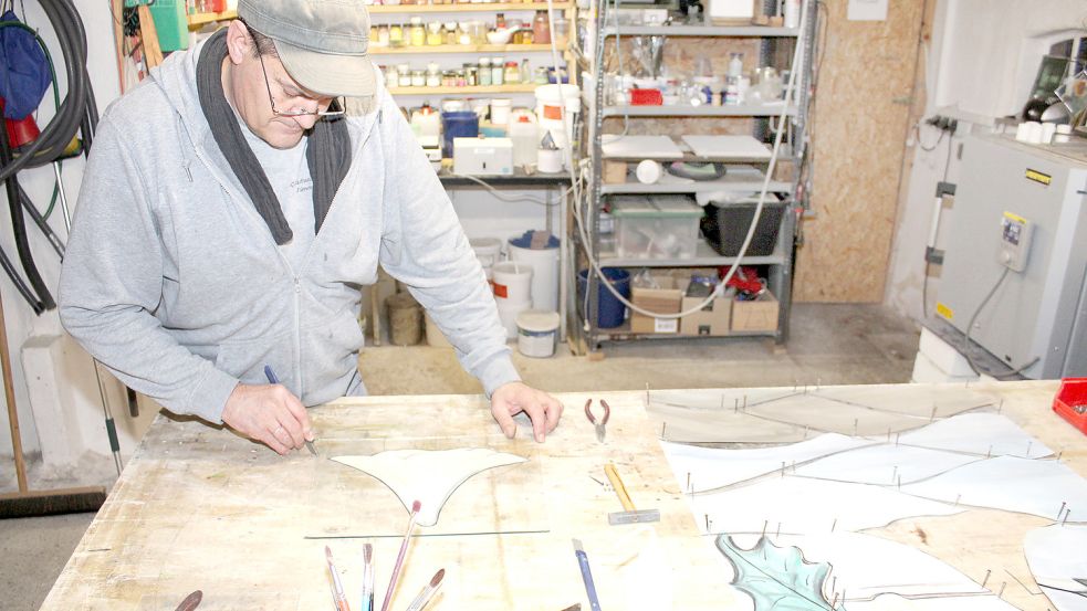 Konzentriert und mit sicherer Hand schneidet Markus Timme an der Schablone einer Stechapfel-Blüte entlang. Das Material, auf der er das Motiv überträgt ist empfindlich: Es ist Glas. Foto: Handwerkskammer