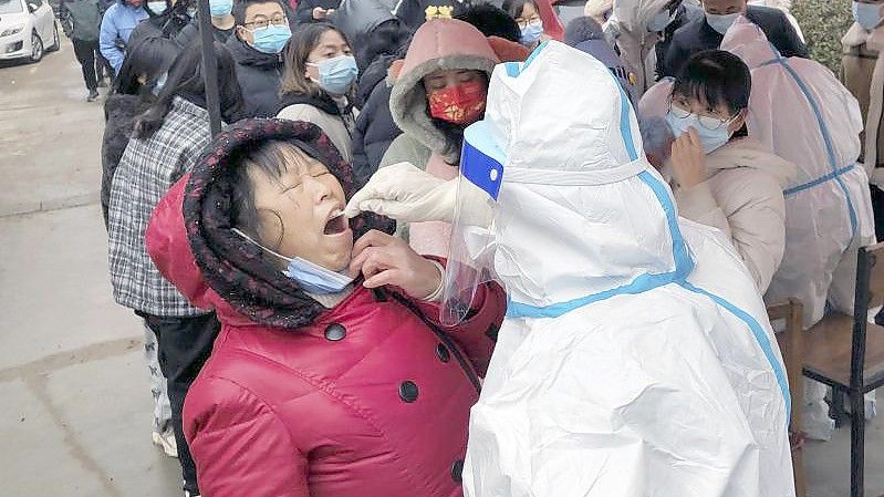 Ein Mitarbeiter des Gesundheitswesens in einem Schutzanzug macht Abstriche für Corona-Tests bei Anwohnern. Foto: CHINATOPIX/AP/dpa