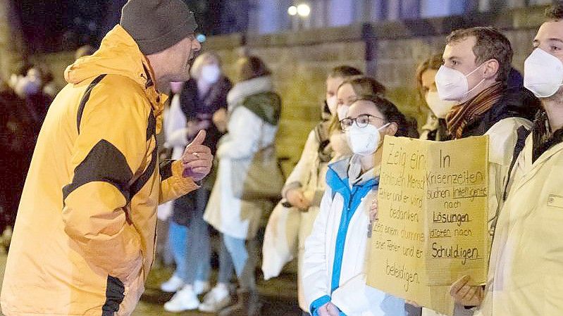 Ein Teilnehmer einer als „Spaziergang“ deklarierten Demo von Impfgegnern und Kritikern der Corona-Maßnahmen redet am Uni-Klinikum Dresden auf zahlreiche Gegendemonstranten ein. Foto: Sebastian Kahnert/dpa-Zentralbild/dpa