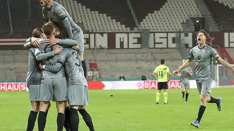 Eigentor durch Dortmunds Axel Witsel (l, am Boden) - 2:0 für St. Pauli. Dortmunds Torwart Gregor Kobel kann nicht eingreifen. Foto: Christian Charisius/dpa