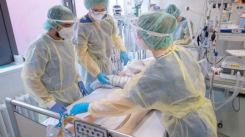 Pflegerinnen und Pfleger sowie eine Ärztin kümmern sich auf der Intensivstation für Corona-Patienten um einen Patienten. (Archivbild). Foto: Sebastian Gollnow/dpa