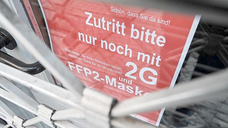 Ein Schild weist am Eingang eines Ladens in der Innenstadt auf die Maskenpflicht und die 2G-Regel hin. (Archivbild). Foto: Felix Kästle/dpa