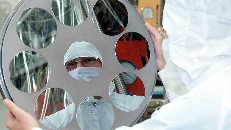 Ein Mitarbeiter der Siltronic AG bei der Herstellung von Siliziumscheiben (Archivfoto). Foto: Matthias Schrader/dpa