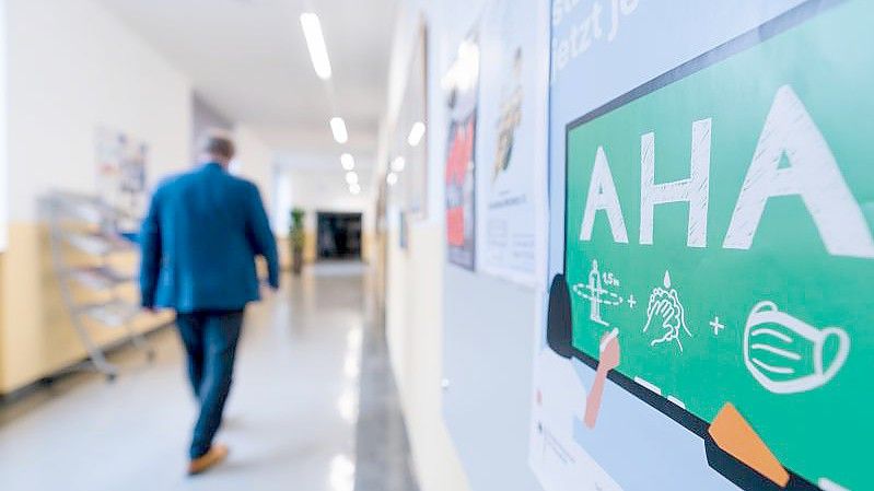An der Wand eines Flurs in einem Gymnasium ist ein Hinweis auf die AHA-Regeln angebracht. Foto: Nicolas Armer/dpa