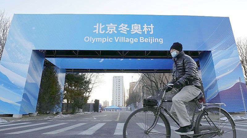 Ein Mann fährt in der Nähe des Athletendorfs in der chinesischen Hauptstadt Peking Fahrrad. Foto: -/Kyodo/dpa