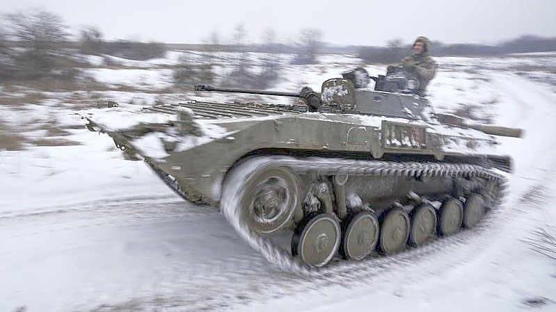 Ukrainische Soldaten fahren mit einem gepanzerten Mannschaftstransportwagen durch den Schnee. Foto: Vadim Ghirda/AP/dpa