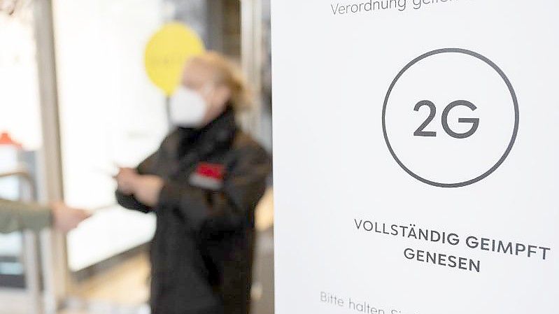 Eine Mitarbeiterin eines Stuttgarter Kaufhauses kontrolliert den Impfnachweis einer Kundin. Foto: Bernd Weißbrod/dpa