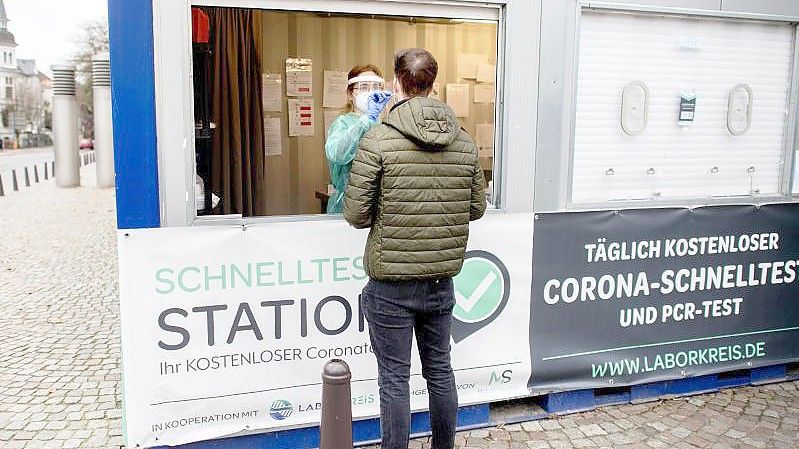 Eine Mitarbeiterin einer Teststation in der Oldenburger Innenstadt nimmt einen Abstrich von einem jungen Mann. (Archivbild). Foto: Hauke-Christian Dittrich/dpa