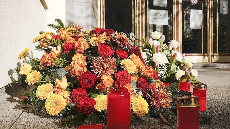 Kerzen und Blumenkränze liegen vor dem Eingang eines Universitätsgebäudes am Botanischen Garten in Heidelberg. Foto: Uwe Anspach/dpa
