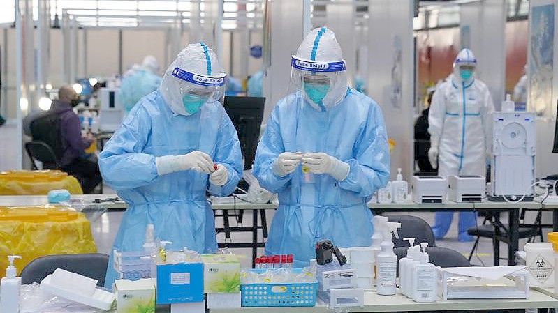 PCR-Prüfer in Schutzanzügen arbeiten in einem Prüfzentrum auf dem Flughafen von Peking. Foto: Andrew Milligan/PA Wire/dpa