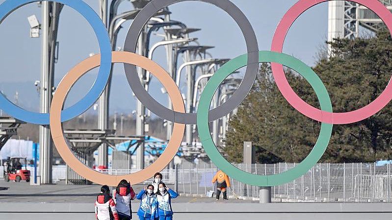 Von Olympia-Stimmung ist in Peking wenig zu spüren: Volunteers stehen vor den olympischen Ringen für ein Selfie. Foto: Peter Kneffel/dpa