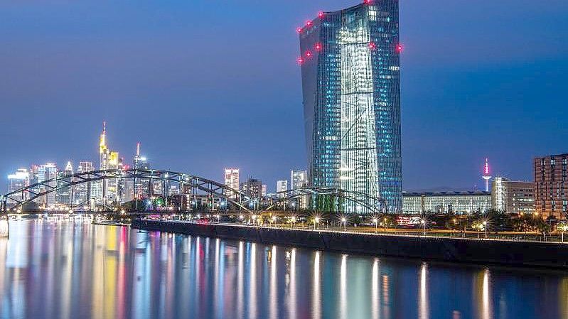 Die Lichter der Europäischen Zentralbank sowie der Frankfurter Bankenskyline spiegeln sich im Main. Foto: Boris Roessler/dpa