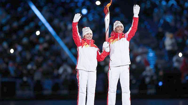 Dinigeer Yilamujiang (l) und Zhao Jiawen mit der Olympischen Fackel bei der Eröffnungsfeier. Foto: Cao Can/XinHua/dpa