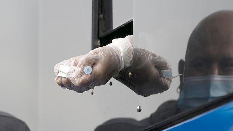 Ein Mitarbeiter des Gesundheitswesens reicht einen Teststab durch ein kleines Fenster in einem mobilen Corona-Testzentrum in Kalifornien. Foto: Jae C. Hong/AP/dpa