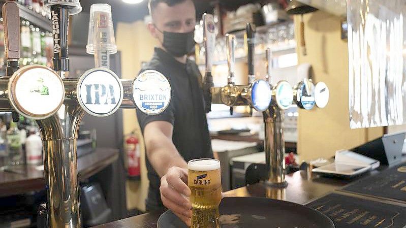 Ein Mitarbeiter eines Pubs serviert ein Bier. Trotz weitreichender Lockerungen von Corona-Regeln haben britische Pubs erneut deutlich weniger Bier verkauft als vor der Pandemie. Foto: Jon Super/AP/dpa